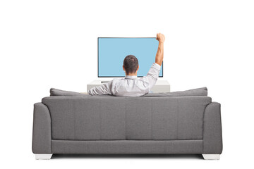 Rear view shot of a man in front of tv sitting on a sofa and cheering