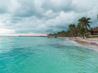 pacific fisherman beach with palm trees turquoise waters, and a cloudy sky 