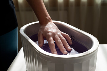 Parafinbad. Hand im Wachsbad. Ergotherapie, Physiotherapie. Behandlung mit Flüssigwachs