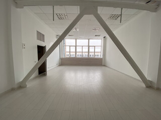 Fototapeta premium Empty modern loft room with large windows and structural beams, highlighting a spacious and bright interior. Room minimalist design for various uses and creativity.