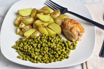 baked chicken thigh  with potatoe wedges and peas
