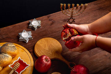 Female hands breaking a pomegranate on the table in Rosh Hashanah