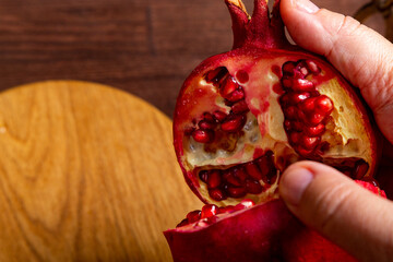 Female hands breaking a pomegranate on the table in Rosh Hashanah next to an apple challah