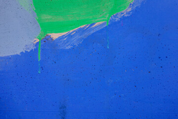 Messy green paint strokes on old purple painted wall. Color drips, flows, streaks of paint on...