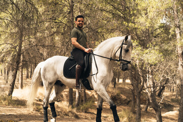 Fototapeta premium Young owner of a white horse walking along a mountain trail with his horse. Concept of enjoyment with pets