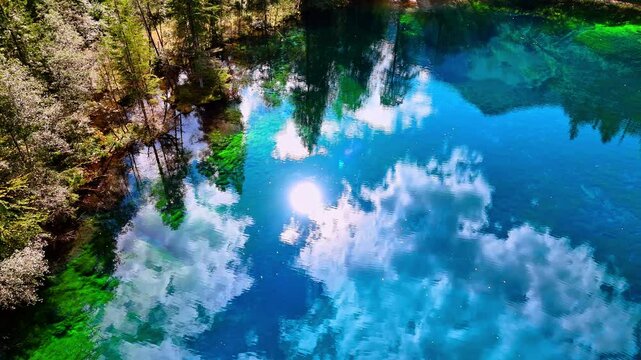 Amazing azure sky with sun and white clouds reflecting in the lake. Aerial perspective on the Christlessee lake, Oberstdorf, Bavarian Alps, Europe.