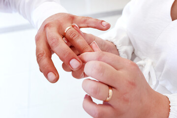 The bride puts a gold wedding ring on the groom's finger. Wedding ceremony.