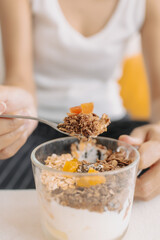 Happy asian woman eating healthy homemade snack made of yogurt.