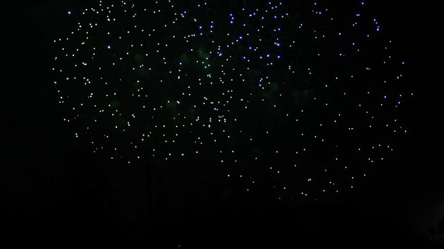 Silver blue green sparks scattering fireworks on the black night sky. General plan