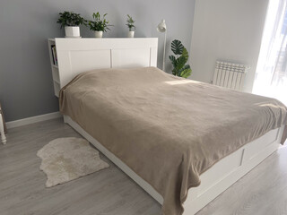 Scandinavian design bedroom with minimalist style and natural light. Home plants and simple cozy bed