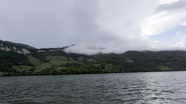 paisaje de una monta&ntilde;a con neblina en la superficie grabada desde una lancha en un rio a un velocidad constante