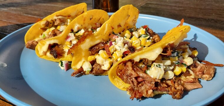 Delicious smoked brisket tacos topped with fresh corn and herb salsa, served on a sunny day for a perfect outdoor meal.