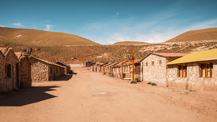 Main street of Machuca, a small, peaceful village near San Pedro de Atacama in Chile, on the altiplano at an altitude of 4000m. The street is lined with traditional adobe houses under a clear sky.