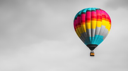 Obraz premium Vibrant Colorful Hot Air Balloon Contrasting with Gray Sky Monochrome Background