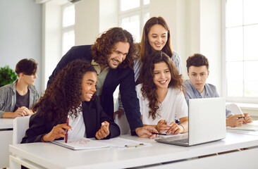 Group of high school students and classmates sitting in the classroom with male friendly smiling...