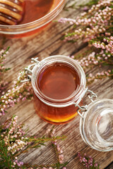 Herbal syrup in a glass jar with fresh wild heather flowers on a wooden table