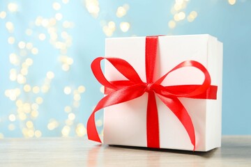 Beautiful gift box on table with shining bokeh behind