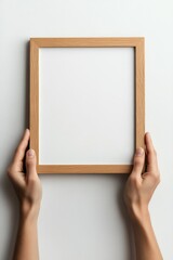 Obraz premium Hands holding a wooden frame, empty, white background.