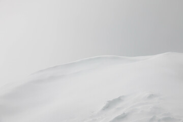 Fototapeta premium Minimalist Winter Landscape featuring Vast expanse of gently rolling Snowcovered Hills partially obscured by a soft mist. Solitary distant object adds focal point, creating serene and tranquil scene
