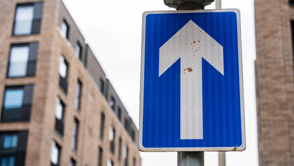 Blue One-Way Traffic Sign with Urban Building Background