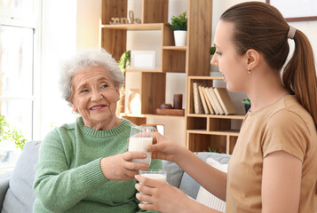 Senior woman with her granddaughter drinking milk at home