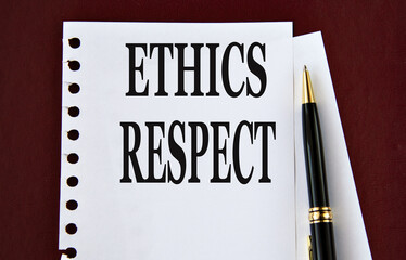 ETHICS RESPECT - words on a white sheet on a brown background with a pen