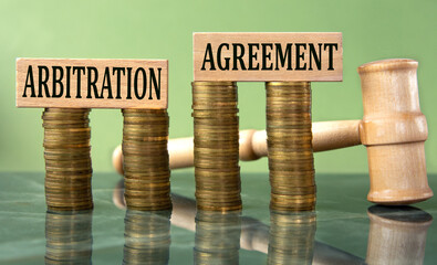 ARBITRATION AGREEMENT - word on a white sheet with a judge's gavel and a stack of coins in the background