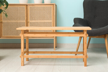 Coffee table with armchair and dresser near blue wall