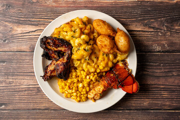 Caption: Tasty Caribbean food served on a white plate or white bowl on a rustic vintage wooden table backdrop - colorful home cooked meals and desserts with chicken, chips, vegetables, rice, bbq, stew