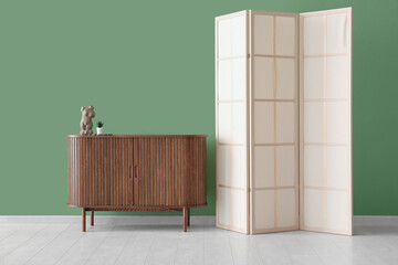 Folding screen and cabinet near green wall