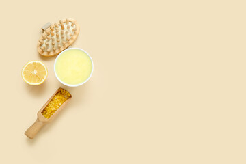 Bowl of lemon body scrub with sea salt and massage brush on beige background