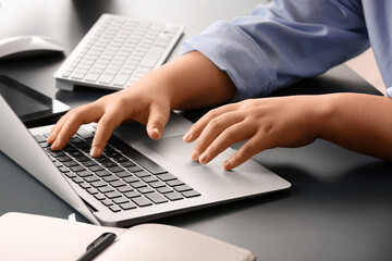 Female programmer typing on laptop keyboard at her workplace in office, closeup