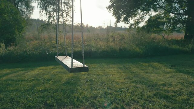 lonely outdoor wooden seat swing at countryside scenery summer evening sunset slow motion