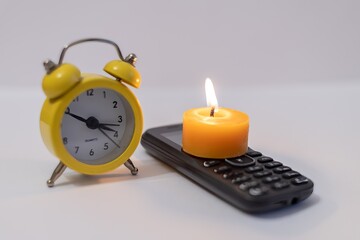 Burning candle on phone next to alarm clock. Power outage due to war in Ukraine