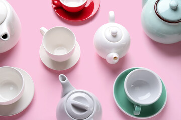 Composition with different cups and teapots on pink background