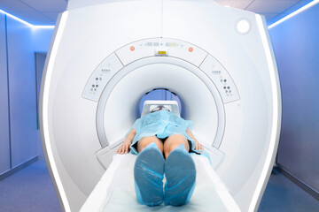 MRI and CT medical center. the patient lies on the table during the examination of his body. large bright room with modern equipment. shoe covers and clothes are covered with a sterile gown. cozy blue