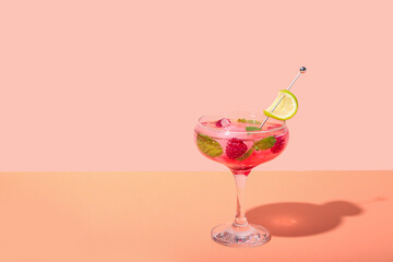 Glass of fresh raspberry mojito on colorful background