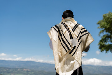 Jewish Man in Tallit Meditating During Morning Prayer Outdoors Under a Blue Sky