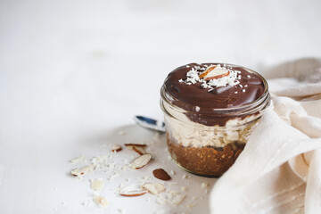 Homemade chocolate overnight oatmeal with shredded coconut and sliced almonds. Selective focus with blurred foreground and background. A joy to eat for breakfast or snack.
