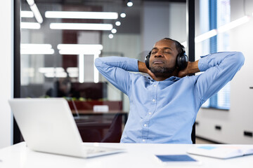 Business professional enjoys relaxation with headphones while sitting at desk. Break from work...