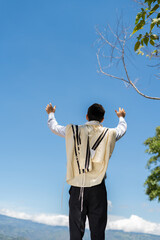 Young Jewish Man with Tallit and Kipa, Hands Raised to the Sky in Worship Outdoors Under a...