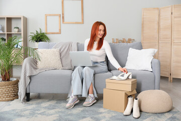 Young woman using laptop with new shoes at home