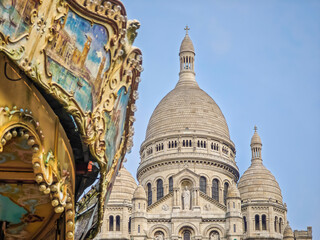 Obraz premium Fragment of colourful carousel with Basilique Du Sacre Coeur de Montmartre. Close up photo of Sacred heart iconic white-domed church in Paris, France
