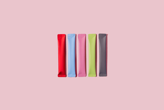 Colorful portion packs or stick packets on pastel pink background. System detox, energy booster or wellness complex concept