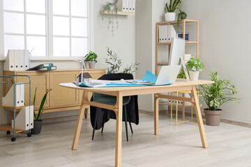 Interior of engineer's office with workplace, wind turbine model and plants