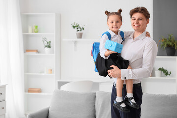 Obraz premium Little girl with school lunchbox and her father at home