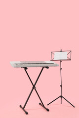 Modern synthesizer and stand with notes on pink background