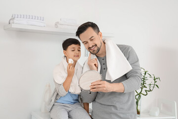 Fototapeta premium Happy father and his little son with holding with shaving foam on brush in bathroom