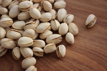 Roasted and salted pistachios in bowl on wooden table, side view.