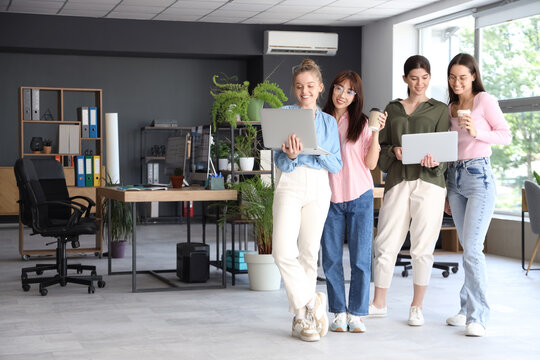 Team of female programmers with laptops and coffee in office